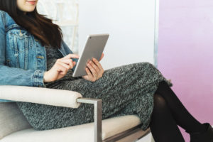 Woman sitting in waiting room looking at tablet